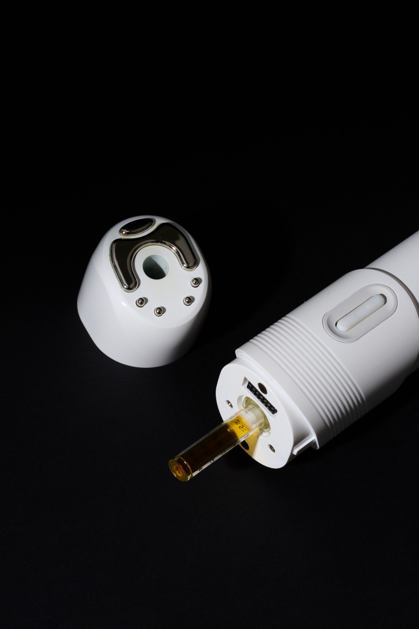 Close-up of the AET-Shot treatment head and handpiece on a black background